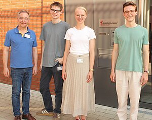 Leo Wittenbecher, Oskar Mahler, Ida Schulze Tast und Thomas Mählmann stehen nebeneinander vor dem Eingang der Seelsorge am Universitätsklinikum Münster und lächeln in die Kamera. Leo Wittenbecher, Oskar Mahler, Ida Schulze Tast und Thomas Mählmann stehen nebeneinander vor dem Eingang der Seelsorge am Universitätsklinikum Münster und lächeln in die Kamera.