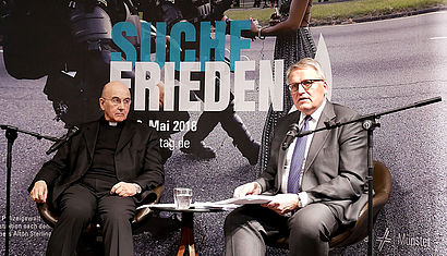 Bischof Genn und ZdK-Präsident Thomas Sternberg sitzen während der Pressekonferenz auf der Bühne.