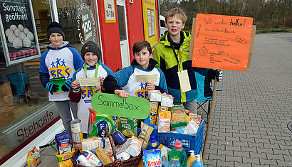 Schüler nehmen Lebensmittelspenden vor einem Supermarkt entgegen.