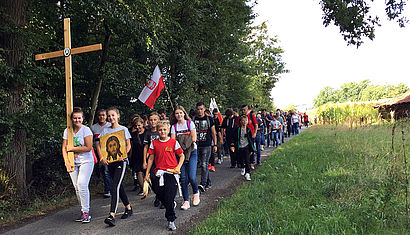 Jugendliche tragen bei ihrer Wallfahrt ein Kreuz an der Spitze. 