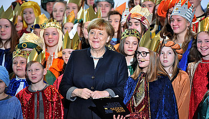 Inmitten einer Gruppe von Sternsingern steht Bundeskanzlerin Angela Merkel.