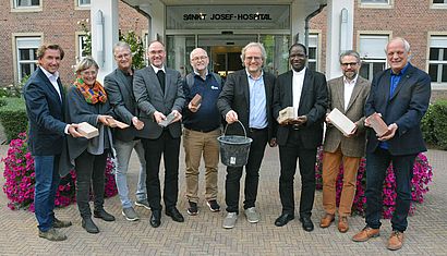 Zahlreiche Menschen stehen vor einer Glastür mit dem Schriftzut St.-Josef-Hospital.