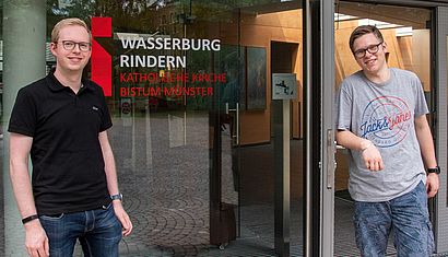 Zwei Männer stehen am Eingang der Wasserburg Rindern.