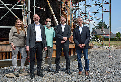 Sandra Kimm-Hamacher, Weihbischof Rolf Lohmann, Hans Günter Nass, Dr. Dominik Pichler und Hans-Josef Bruns (v.l.) stehen vor der Baustelle des Gradierwerks. Im Hintergrund ist ein Baugerüst zu erkennen.