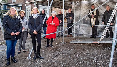 Mehrere Menschen stehen mit Abstand vor einem eingerüsteten Gebäude.