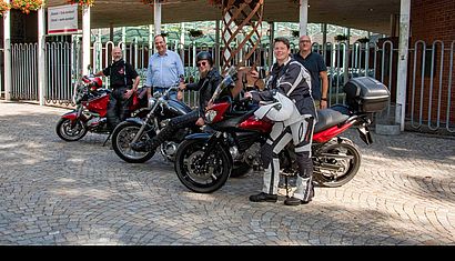 Mehrere Personen stehen mit drei Motorrädern vor dem Forum Pax Christi.