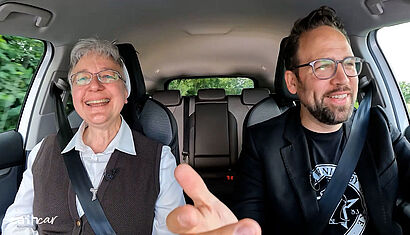 Sr. Katharina Kluitmann und Moderator Christoph Tiemann lachen während ihres Gesprächs im Auto. 