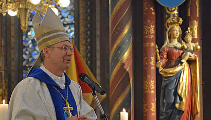 Weihbischof Stefan Zekorn steht an einem Mikrofon im Altarraum der Marienbasilika in Kevelaer. Auf der rechten Seite ist eine Marienfigur zu sehen.