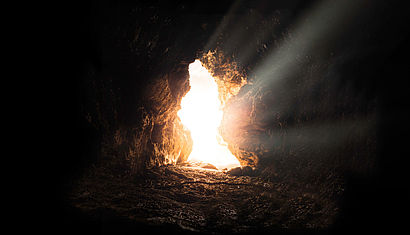 Durch eine Öffnung im Fels fällt Licht in eine Grabhöhle.