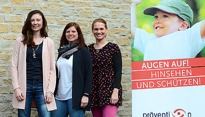 Die drei Präventionsfachkräfte stehen vor einer Hauswand.