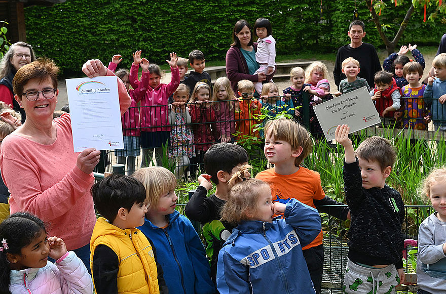 Monika Rolfes, Leiterin der Kita St. Nikolaus in der Münsteraner Innenstadt, freut sich mit den Kindern über die erfolgreiche Auszeichnung als „Öko-faire Einrichtung“.