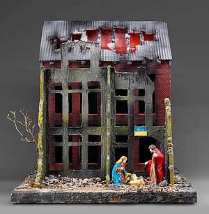 Maria, Josef und das Jesuskind in einer Krippe in einem zerstörten Haus, an dem eine ukrainische Flagge mit Friedenstaube hängt. Maria, Josef und das Jesuskind in einer Krippe in einem zerstörten Haus, an dem eine ukrainische Flagge mit Friedenstaube hängt.