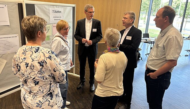Menschen an einer Stellwand in eine Diskussion vertieft