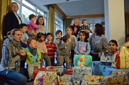 Hinter einem Berg aus Geschenken warten Kinder.