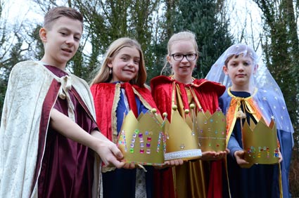 Die Sternsinger Sophia, Mila, Hannes und Henning präsentieren ihre goldenen Kronen. 