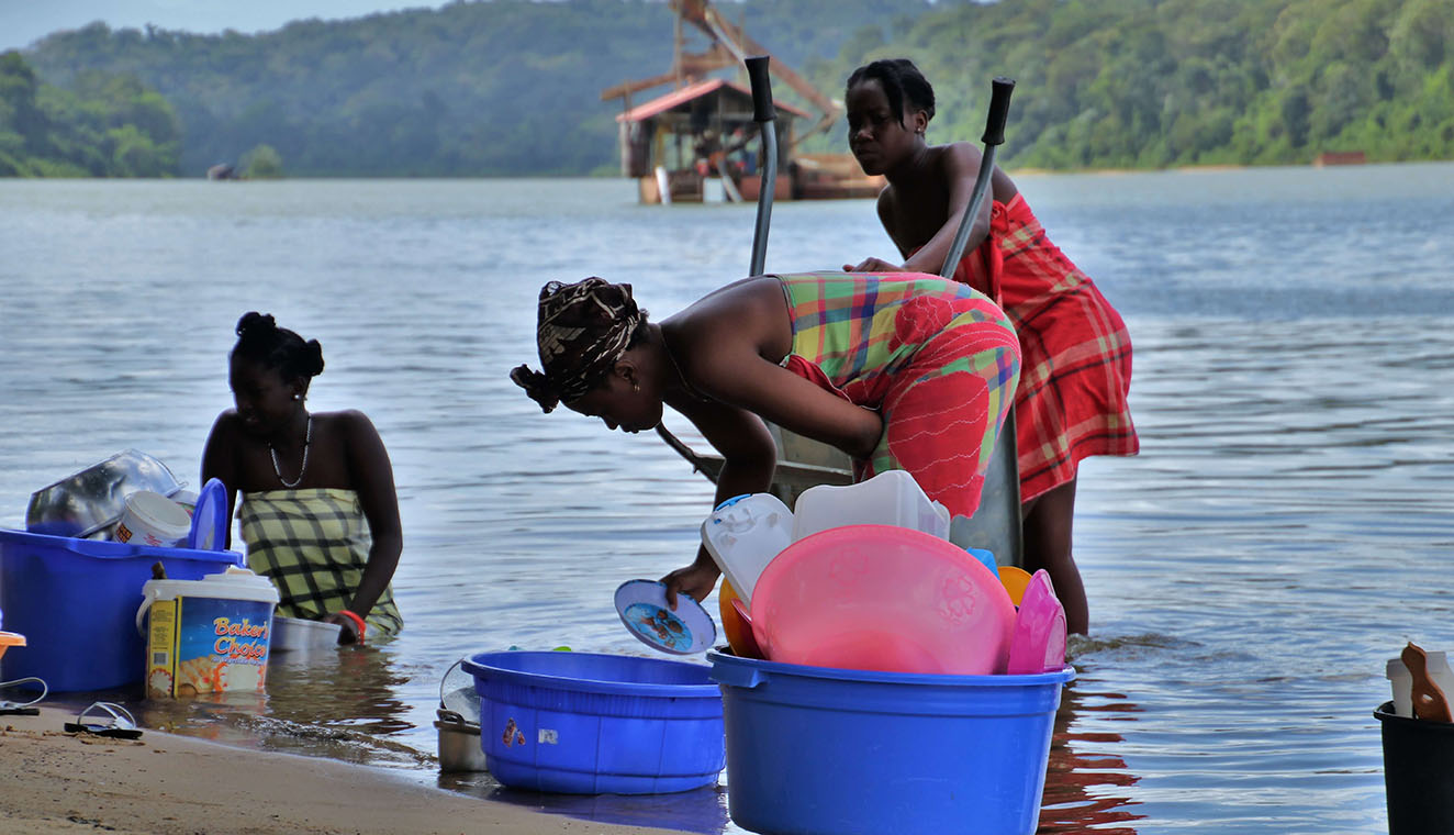 Frauen waschen ihr schmutziges Geschirr im Fluss. 