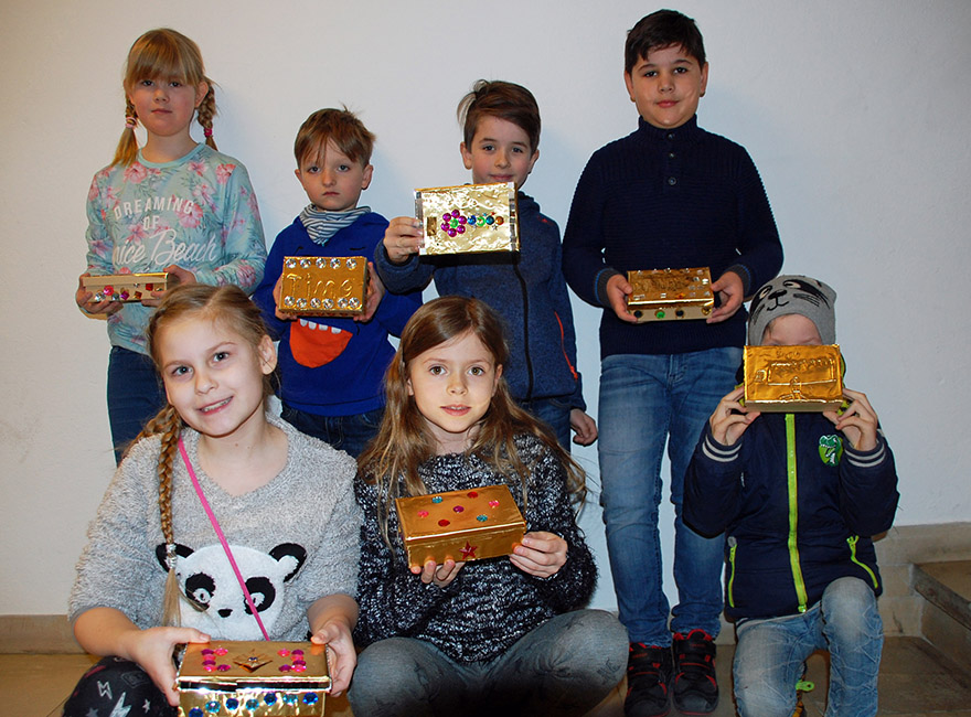 Kommunionkinder präsentieren ihre fertigen Schatzkisten.