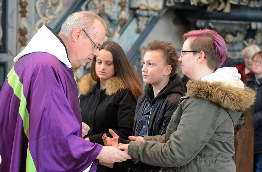 Pater Gottfried salbt die Hände der Taufbewerber.