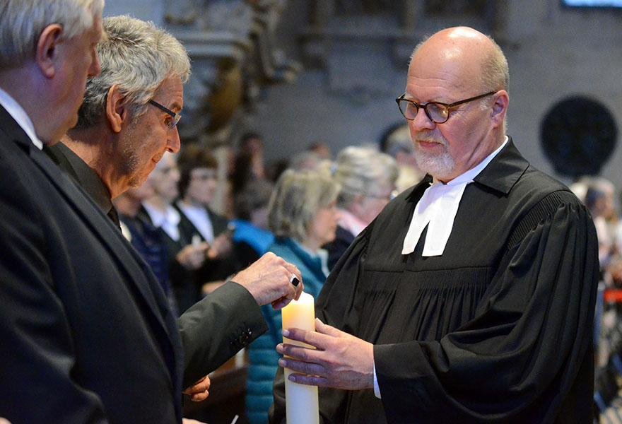 Superintendent Ulf Schlien gibt das Licht der Osterkerze an die im Dom Versammelten weiter.