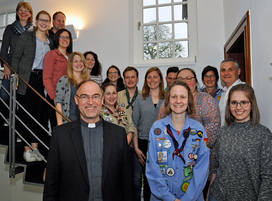 Weihbischof Rolf Lohmann steht im Regionalbüro vor einer großen Treppe, auf der Vertreter verschiedener Jugendverbände stehen.