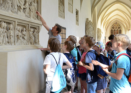 Bildhauer Hetzel erklärt Kinder die Steinarbeiten im Dom.