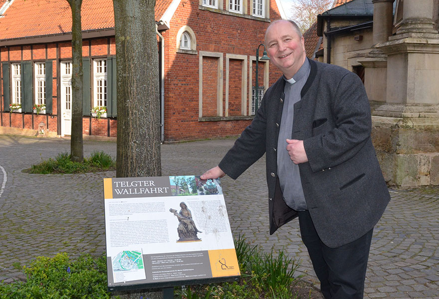 Propst Langenfeld steht neben dem neuen Hinweisschild. 