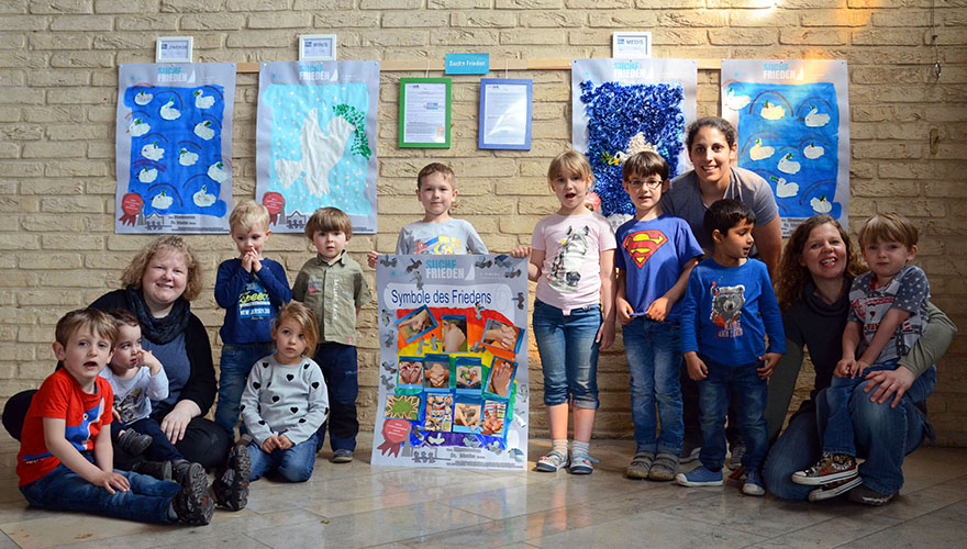 Die Kinder der Kita sitzen vor den Friedensurkunden in der Kirche. 