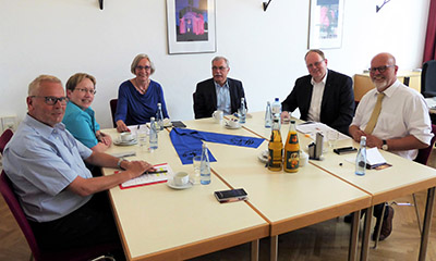 ACK-Vorstandsmitglieder und Vertreter der katholischen und evangelischen Kirche sitzen zusammen am Tisch.