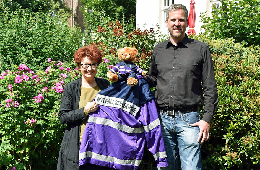 Alexandra Hippchen und Andreas Naumann-Hinz halten gemeinsam eine Jacke der Notfallseelsorge in den Händen.