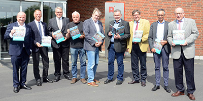 Vertreter des Aschendorff-Verlag und des Katholikentagesbüros haben jeweils ein Buch in der Hand. 