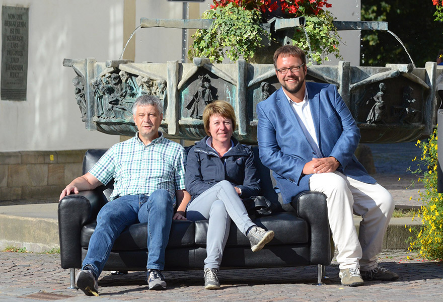 Vertreter der Pfarrei St. Laurentius in Warendorf sitzen auf einem schwarzen Ledersofa auf dem Marktplatz.