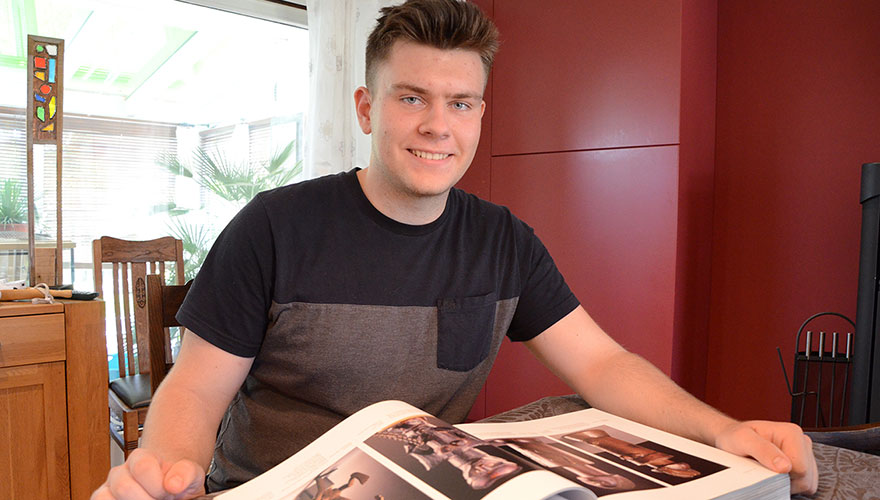 Jannik May sitzt am Tisch und schaut in die Kamera.