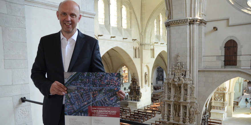Dompropst Kurt Schulte steht auf einer Balustrade oberhalb des Dom-Innenraums. In seinen Händen hält er ein Plakat der Vortragsreihe DomGedanken. Dompropst Kurt Schulte steht auf einer Balustrade oberhalb des Dom-Innenraums. In seinen Händen hält er ein Plakat der Vortragsreihe DomGedanken.