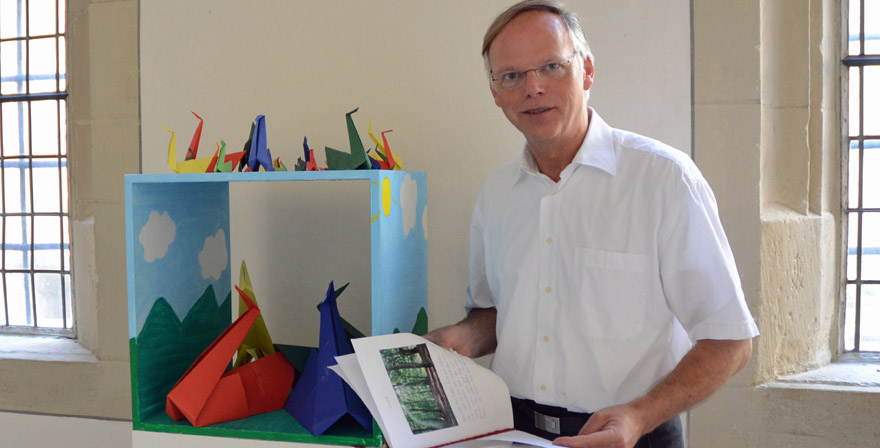 Domkapitular Dr. Klaus Winterkamp zeigt eines der Kunstwerke und blättert in einem Informationsheft. 