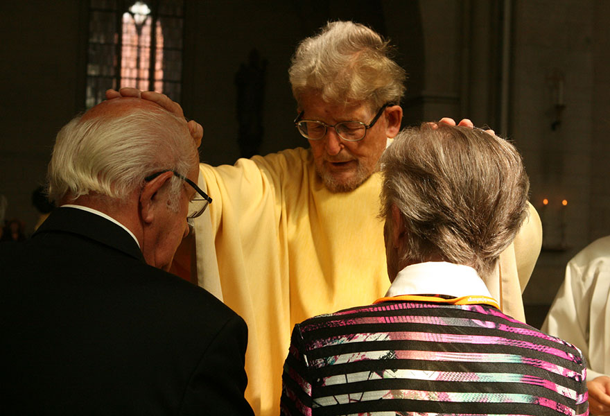 Pater Wolfgang Abeler legt einem Paar zum Segen die Hände auf. 