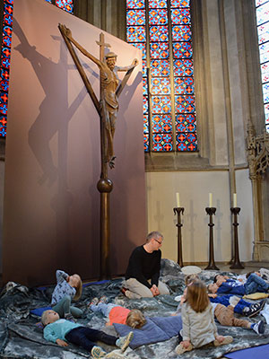 Unter dem Coesfelder Kreuz liegen Kinder und schauen hinauf.