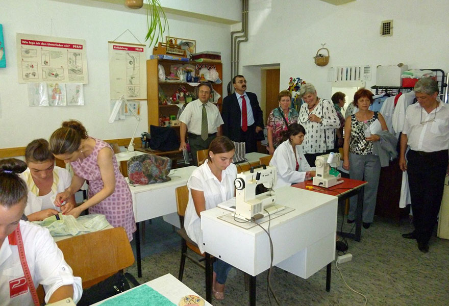 Gäste besuchen die Nähwerkstatt und schauen sich an, wie die jungen Frauen arbeiten.