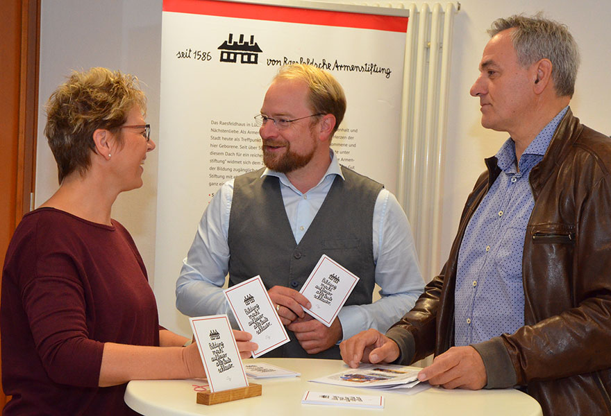 Elisabeth Krechtmann, Boris Sander und Amandus Petrausch stehen an einem Tisch und unterhalten sich.