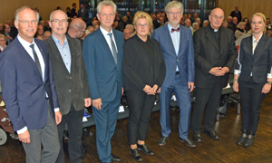 Referenten und Veranstalter stehen in einem großen Saal, dahinter sind viele Zuhörer zu erkennen. Das Bild zeigt von links: Generalvikar Dr. Klaus Winterkamp, An-dreas Gorschlüterz, Antonius Kerkhoff (Direktor der Akademie Franz Hitze Haus), Susanne Kolter, Richard Hoppe-Sailer, Felix Genn und Kim de Wildt.