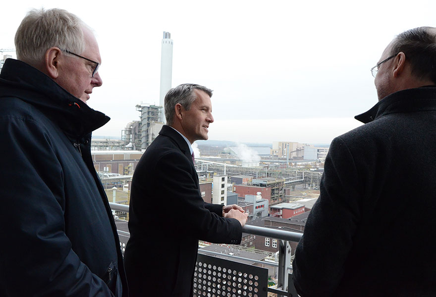 Landrat Cay Süberkrüb, Dr. Jörg Harren und Weihbischof Rolf Lohmann schauen vom Balkon aus auf den Chemiepark in Marl.