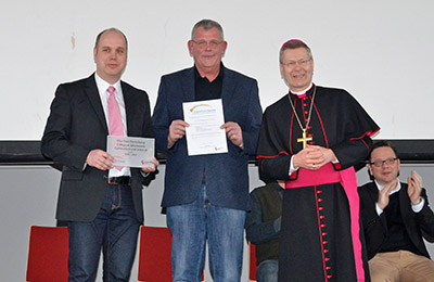 Weihbischof Zekorn überreicht Urkunde und Plakette an Schulleiter und Lehrer. 