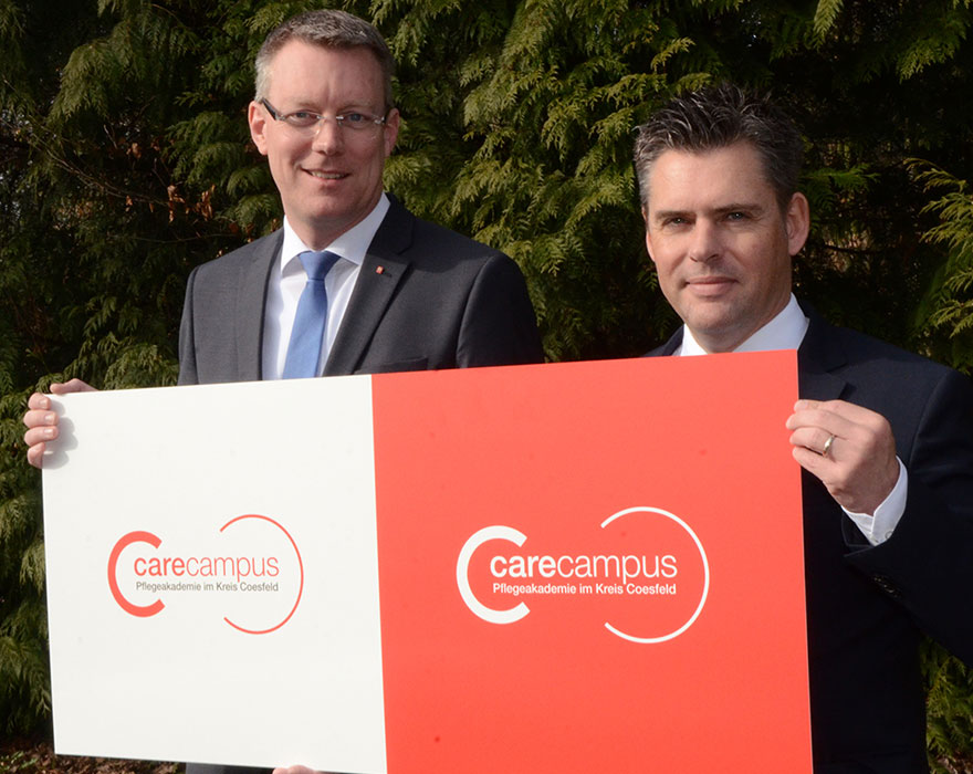 Christian Germing (links) und Dr. Mark Lönnies präsentieren das neue Logo der Pflegeakademie, die carecampus heißt.