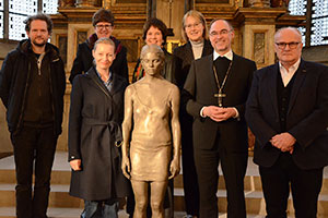 Die Beteiligten haben sich rund um eine Skulptur zum Gruppenbild aufgestellt.