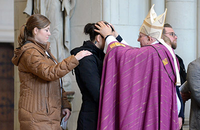 Der Bischof legt Alexandra Grouls die Hände auf den Kopf und segnet sie. 