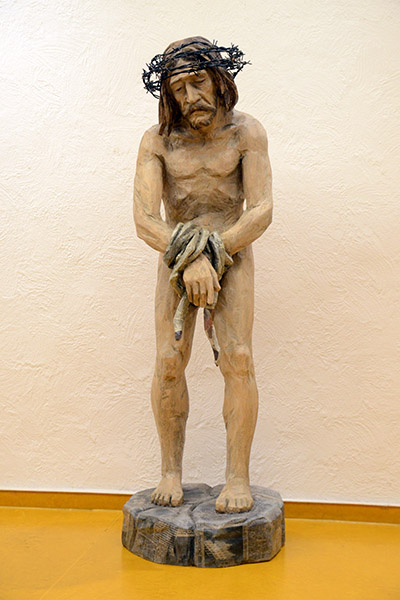 Geschnitzte Christusfigur steht im Kirchenfoyer Geschnitzte Christusfigur steht im Kirchenfoyer