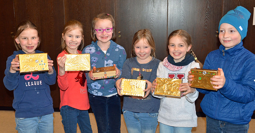 Kinder präsentieren selbstgestaltete Schatzkisten.