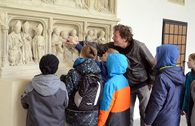 Der Bildhauer zeigt den Kindern Skulpturen im Kreuzgang. Der Bildhauer zeigt den Kindern Skulpturen im Kreuzgang.