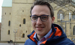 Fabian Guhr steht lächelnd auf dem Domplatz in Münster.