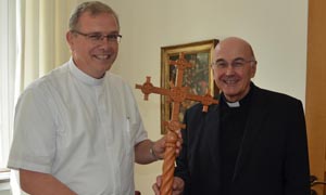 Die Bischöfe Johannes Bahlmann (links) und Felix Genn halten zwischen sich das Kreuz aus hellbraunem Zedernholz.