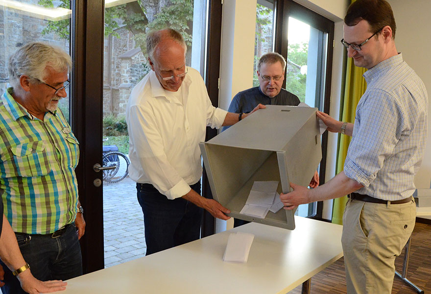 Zwei Männer kippen eine Wahlurne mit Stimmzetteln aus.